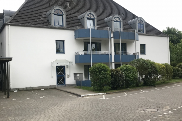 Gebäude mit Eingangsbereich und Parkfläche mit zugewiesenen Parkplätzen je Wohnung