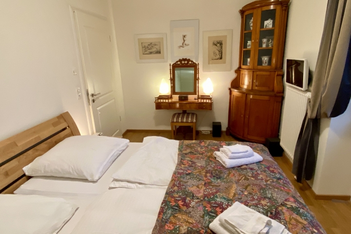 Schlafzimmer 1 mit Toilettentisch und Biedermeiereckschrank mit Meißner Porzellan.