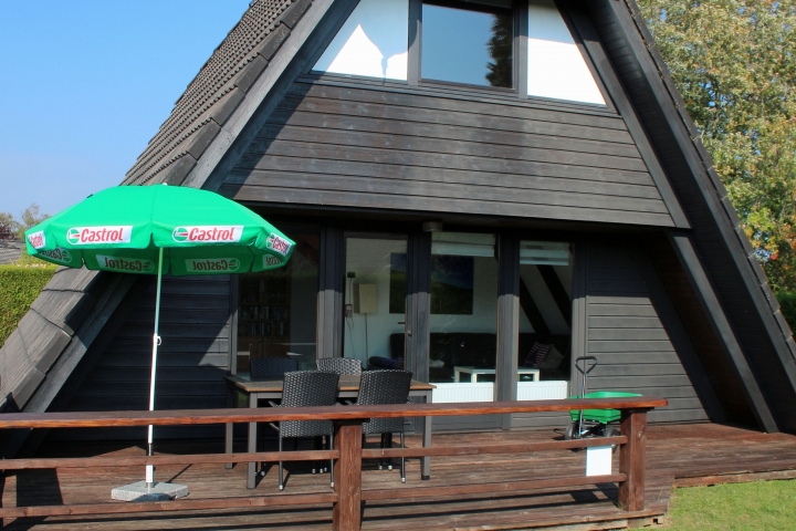 Terrasse mit Liegestühlen, Bollerwagen, Grill, Sonnenschirm, Tisch und Stühle