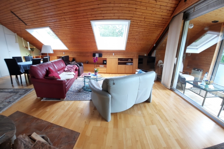 Das Wohnzimmer, mit Eßtisch. Von der offenen Küche aus fotografiert, mit vorgelgertem Verglasten Balkon.
