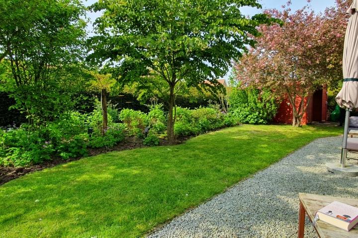 Schön angelegter Garten mit Sonnenliegen und Loungemöbeln. 