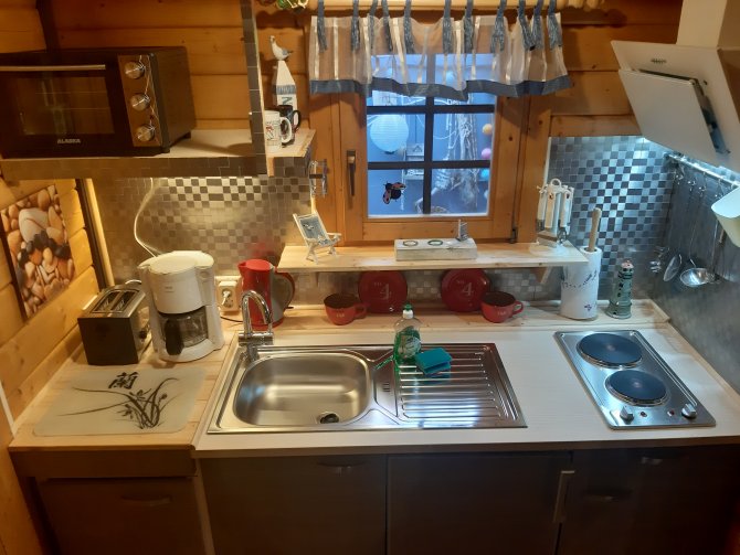 Küche mit Kühlschrank, Toaster, Mikrowelle, Kaffeemaschine, Backofen, Wasserkocher und Kochfeld.