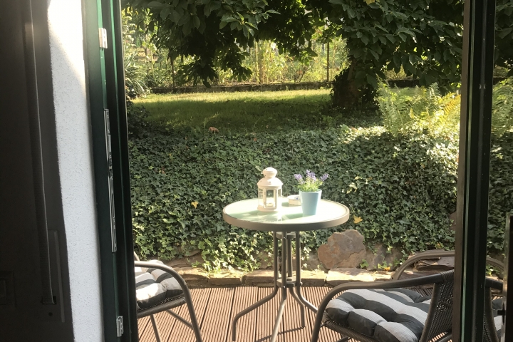 Blick aus Wohnzimmer auf Terrasse und Gartenteil