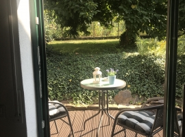 Blick aus Wohnzimmer auf Terrasse und Gartenteil