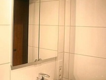 Waschbecken mit Spiegelschrank, der in der Wand eingelassen ist.