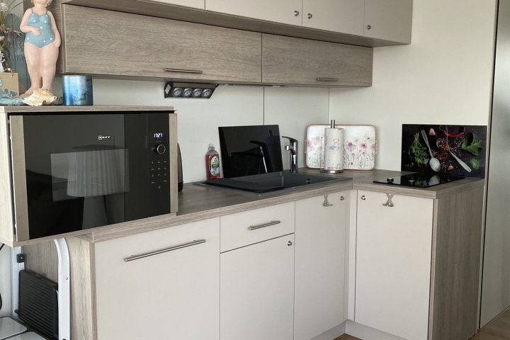 Küche mit Zweiplattenkochfeld, Kühlschrank, Toaster, Eierkocher, Kaffeemaschine, Mikrowelle, Geschirr, Besteck, ...