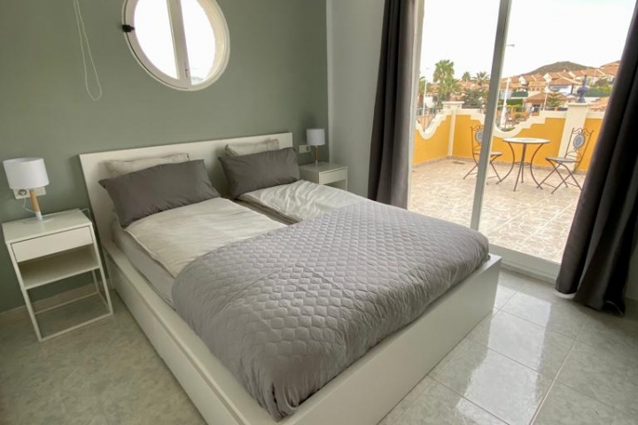 Schlafzimmer im Obergeschoss mit Zugang zur großen Dachterrasse mit Blick zu den Bergen