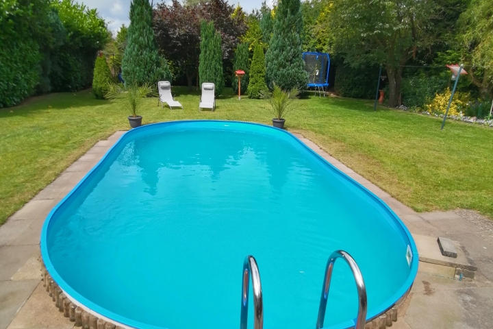 Gartenansicht mit Pool und Wintergarten.