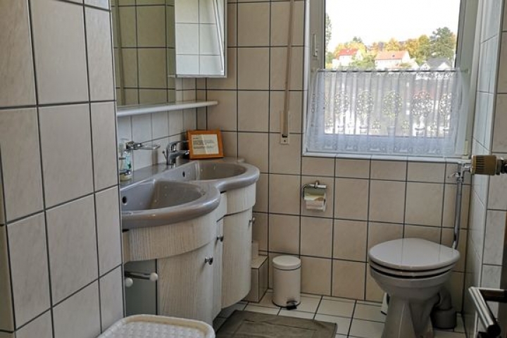 Badezimmer mit Doppelwaschbecken, WC und bodennaher Dusche